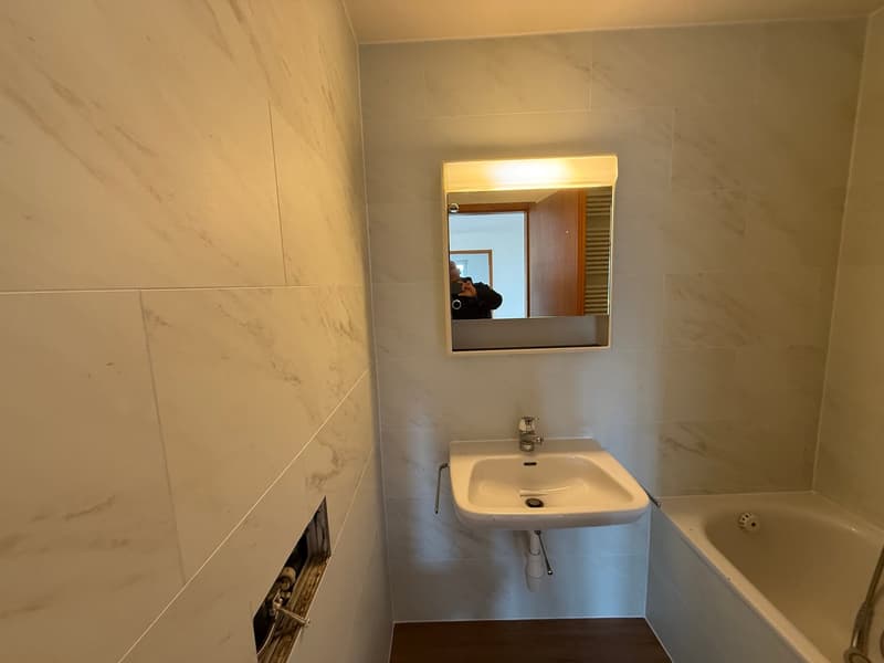 White marble walls, white sink, white bathtub, mirror, no visible floor