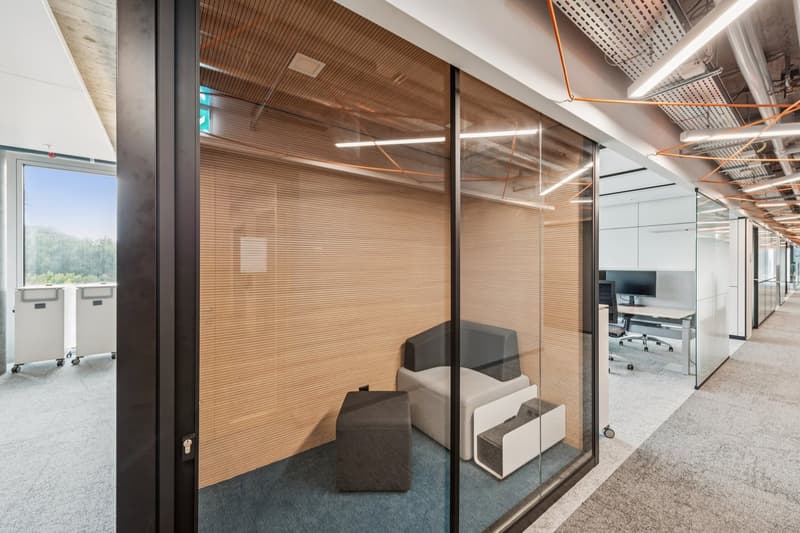 modern office interior, large glass walls, white ceiling, gray and blue flooring, office furniture, views of trees outside