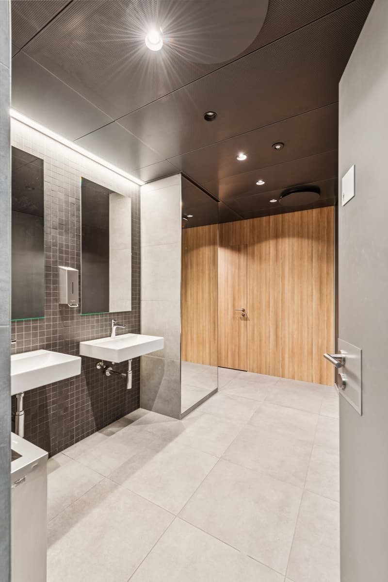 modern design, white tiled floor, white walls, two sinks, wood door, metal door, bright lighting