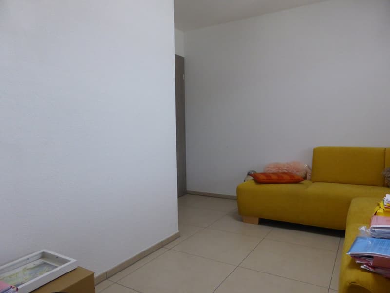 Minimalist design, yellow couch, white walls, tile flooring, door, books