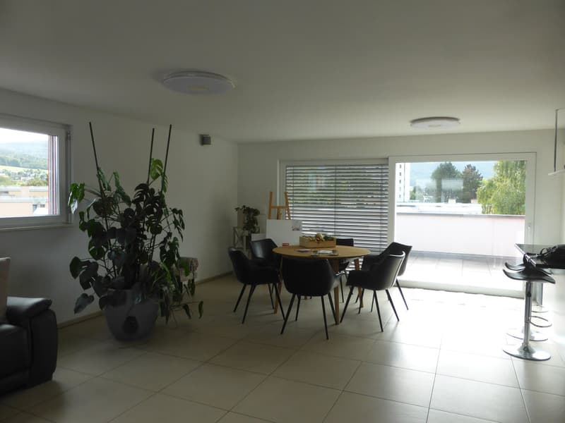 A room that features a dining table, chairs, round table, plants, sliding windows, round lights