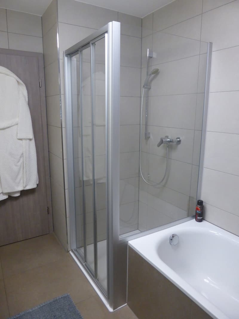 Bathroom with shower, bathtub, and towel hanger.