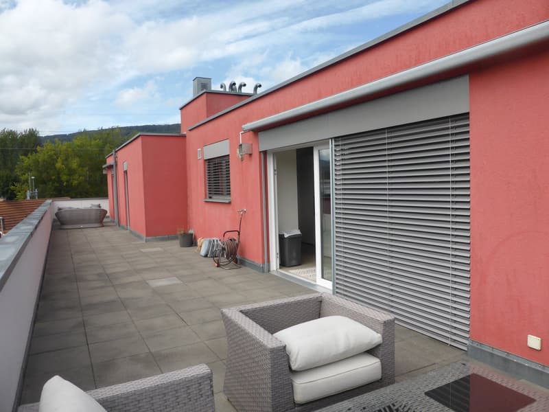 red wall, tiled floor, grey lounge chairs, table, railing, sliding door, grey outdoor blinds