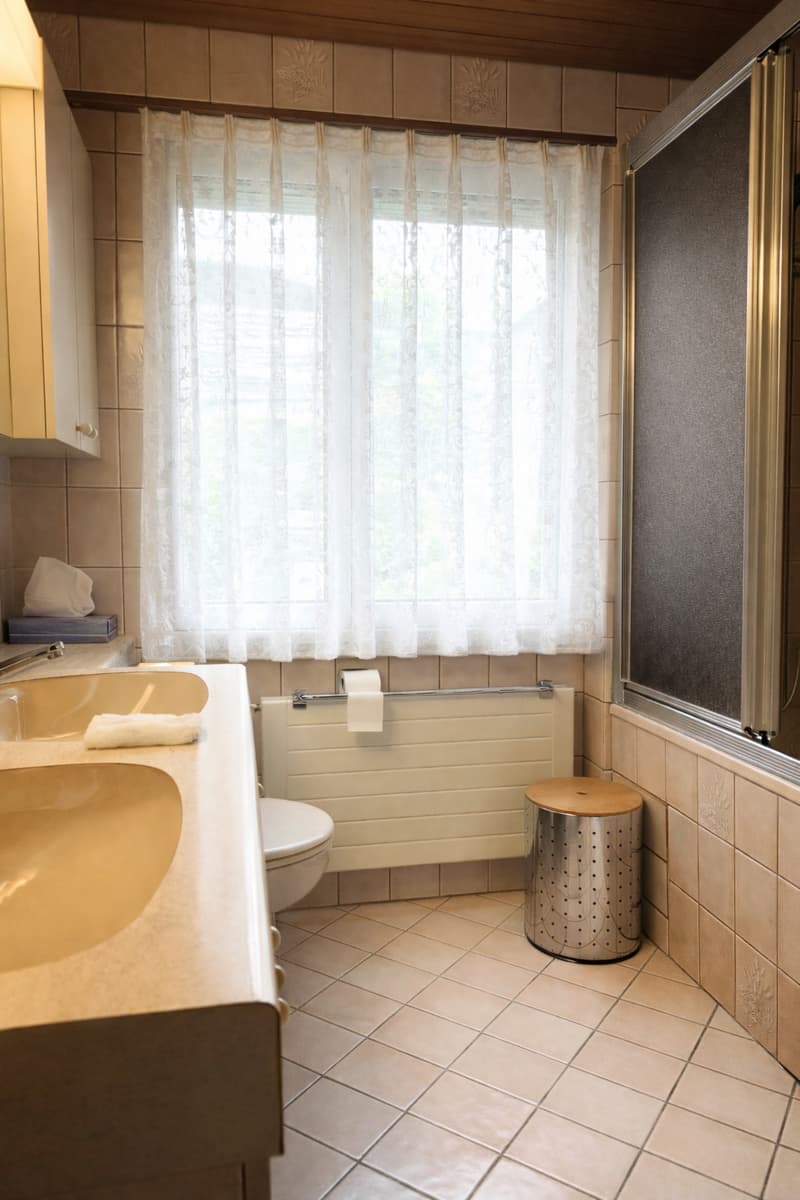 Bathroom with double sink, toilet, shower, and tiled floor.