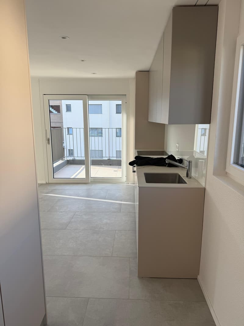 modern kitchen with tiled floor, stainless steel sink, faucet, sliding glass door to balcony, white cabinets, white walls