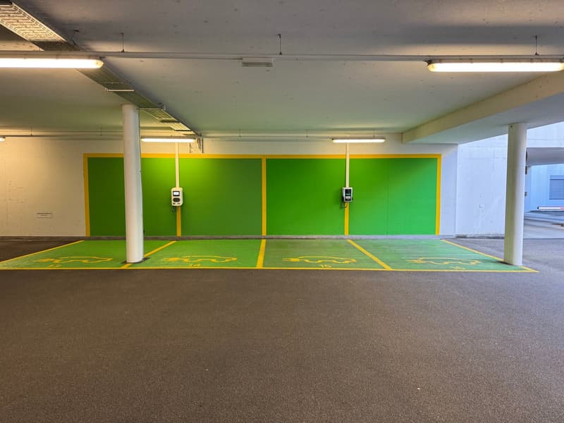 Green and yellow wall, white floor, electric charging station, no cars present