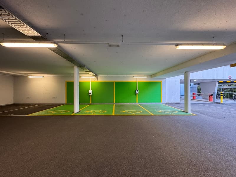 underground parking, charging stations, wide spaces, metal bollards, ceiling lamps