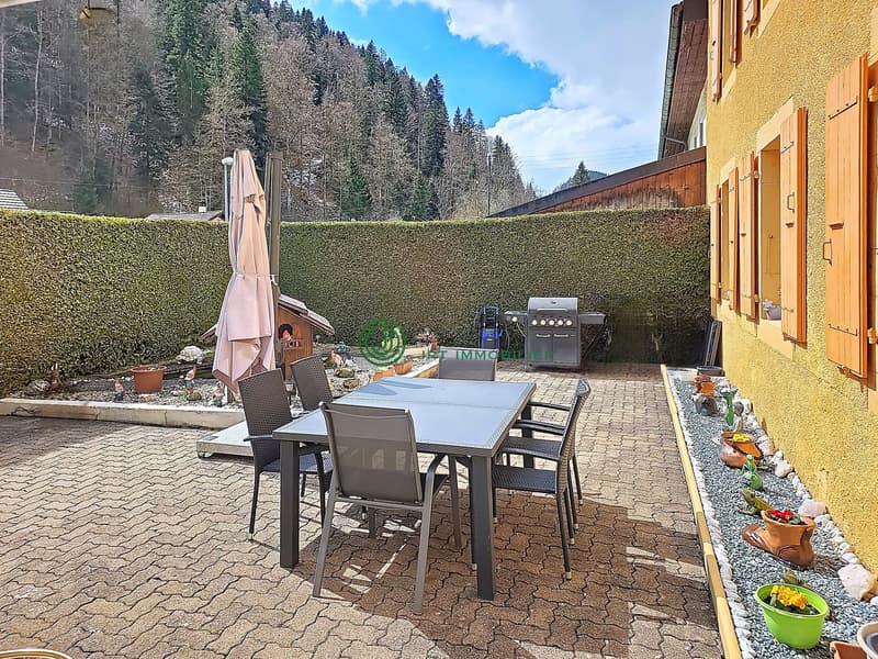 Outdoor dining table and chairs, grill, potted plants, hedge, mountain view