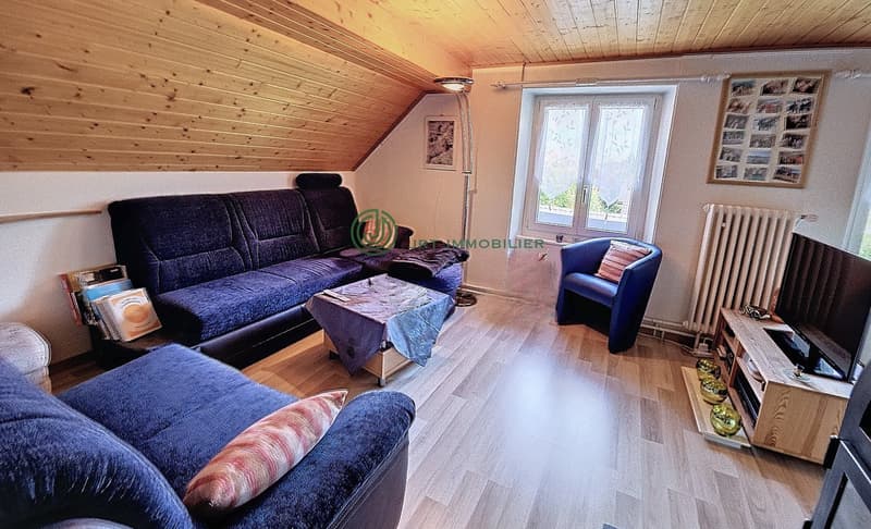 living room with wooden floor, blue couches, coffee table, chair, TV, radiator, wooden ceiling