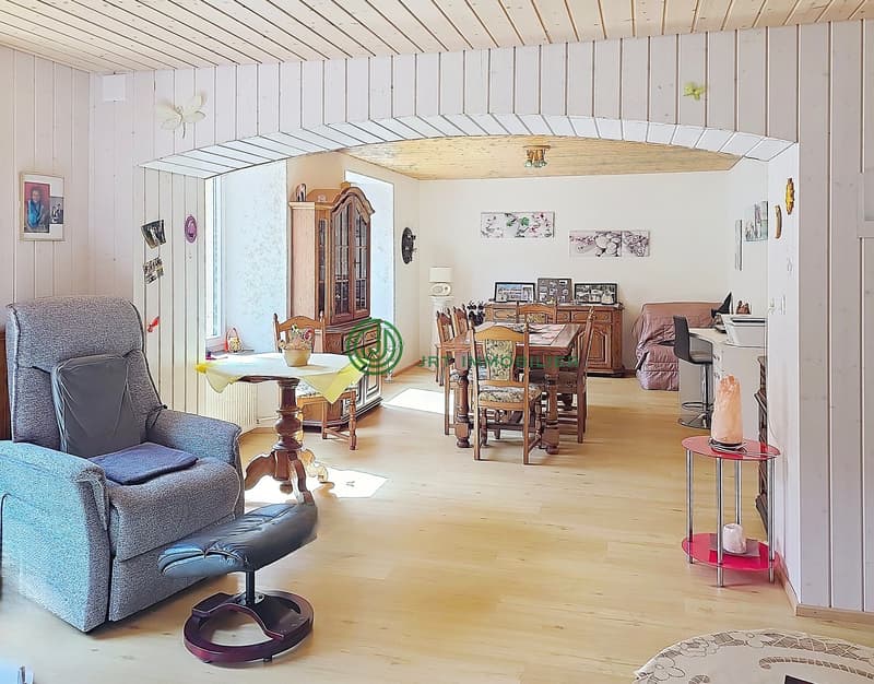 living room with wooden floor, white walls, wooden furniture, dining table, chairs, cabinet, and decorative items