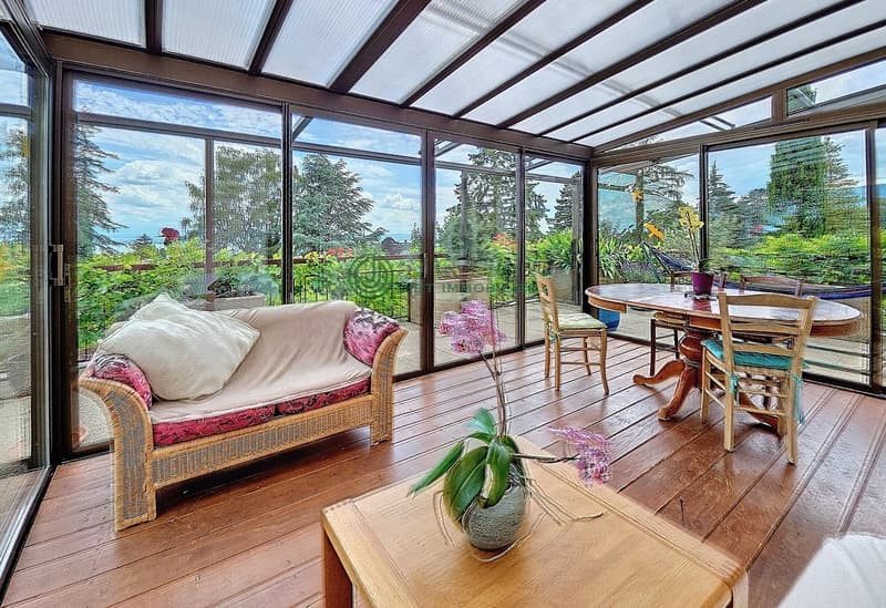 a cozy living area with a wooden sofa, a wooden coffee table with a flower vase, a dining table with chairs and a breathtaking view of the mountains