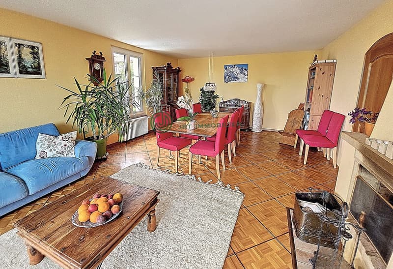 blue couch, wooden coffee table with fruits, dining table and chairs, fireplace, yellow walls, wooden floors