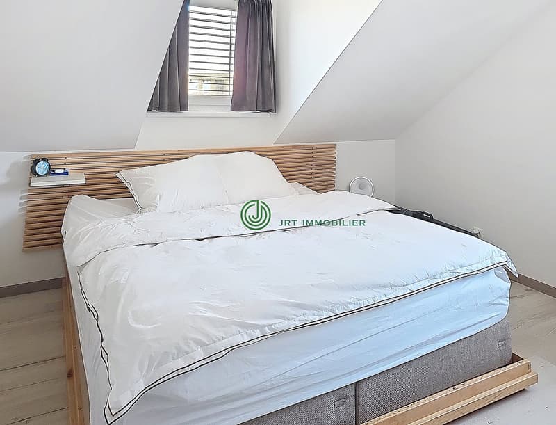Bedroom with wooden bed, white bedding, wooden headboard, window with curtains, wooden floor, white walls