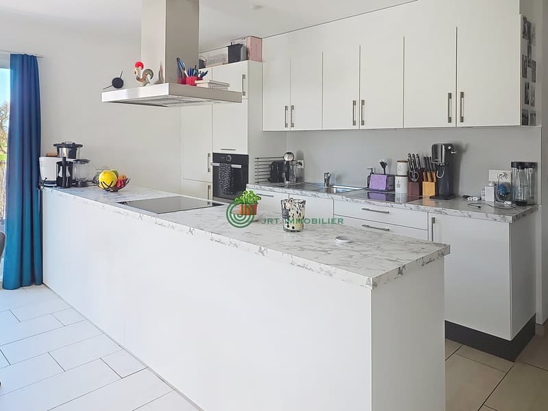 modern kitchen with white cabinets, marble countertop, gas stove, oven, sink, appliances, and a window with blue curtain