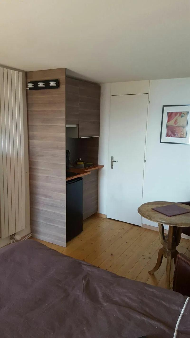 A small bedroom with built-in cabinets, a desk, a bed, and a small table with a radiator.