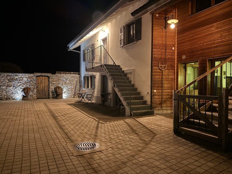House exterior, illuminated stairway, brick walls, wooden sculptures, outdoor seating, illuminated walls