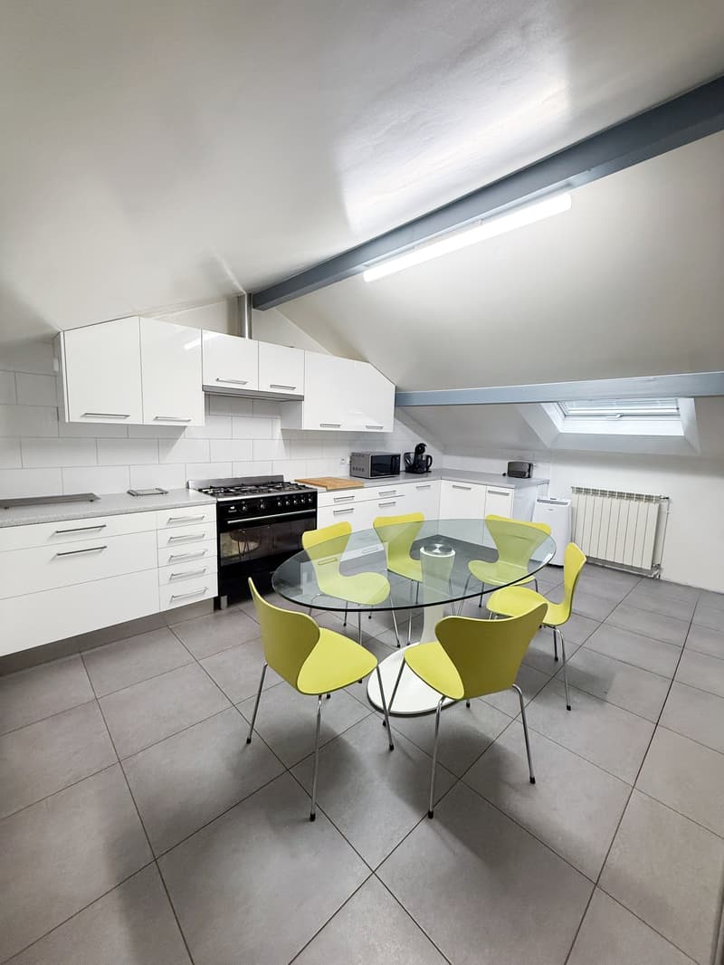 kitchen, 6 yellow chairs, round glass table, white cupboards, gas cooker, oven, toaster, microwave, radiator, ceiling light