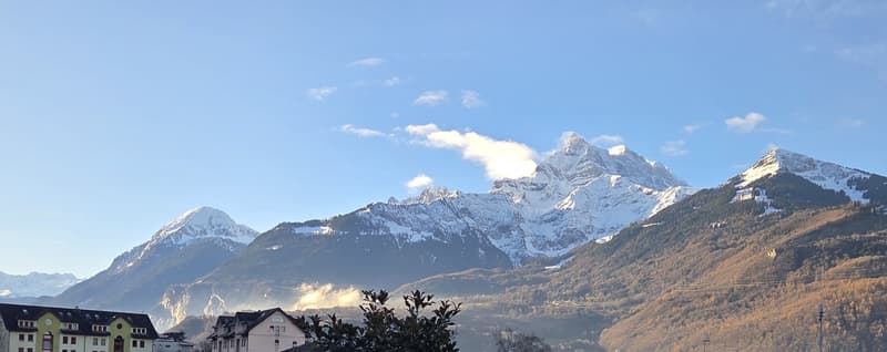 Mountain range covered with snow with buildings in the valley below.