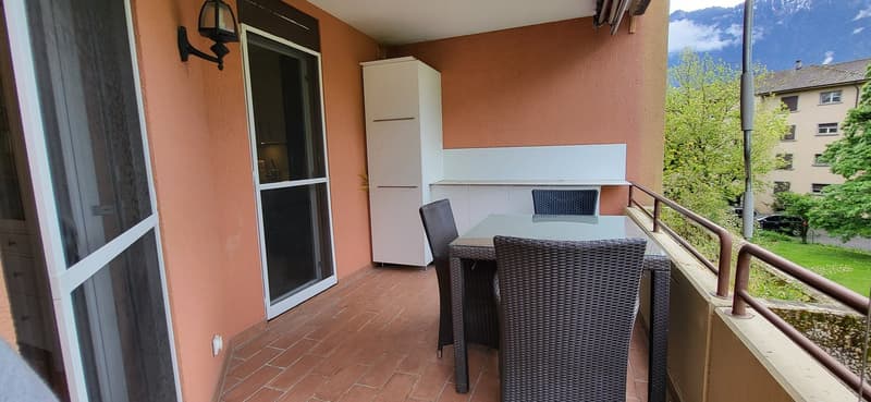 brick walls, large terrace, table and chairs, orange tiled floor, glass sliding door, white cupboards