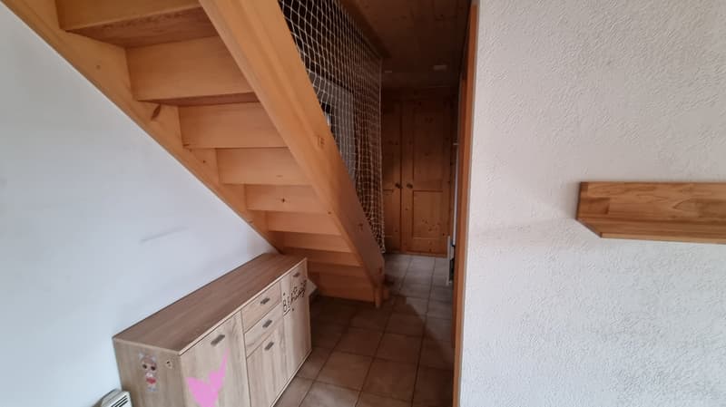tiled floor, wooden stairs, wooden cabinet, radiator, tiled hallway, wooden door, mesh fence