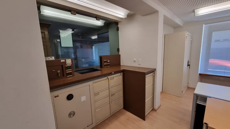 wooden floor, white walls, built-in cabinets, two safe boxes, metal desk