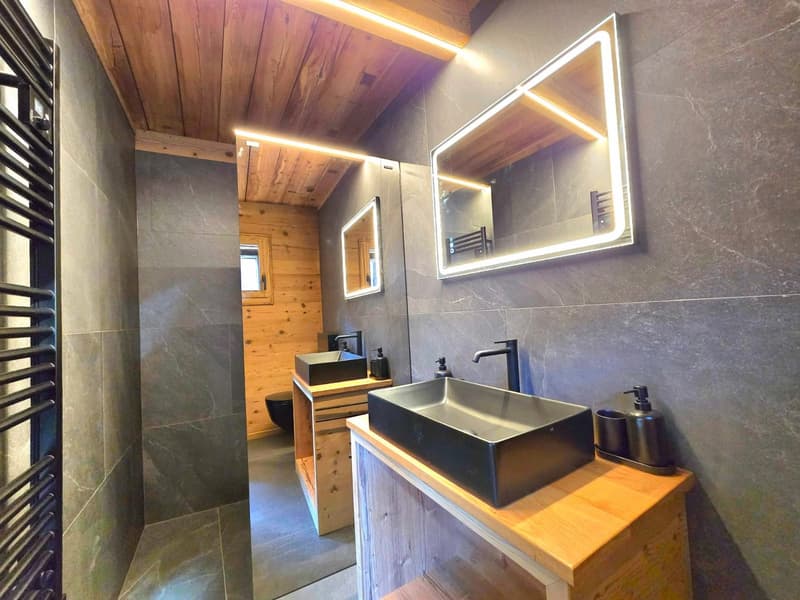 modern bathroom with wooden ceiling, gray tiles, two sinks, large mirror, wooden shelves, toilet