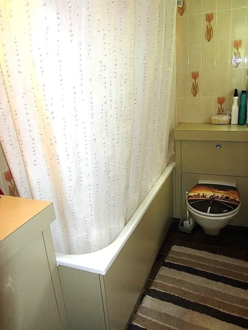 Bathroom with white curtain, vanity cabinet, and toilet