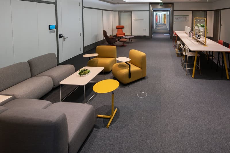 modern office, gray couches, white and yellow tables, orange armchairs, white chairs at long table