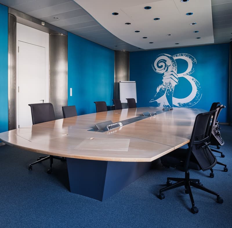 Conference room, blue walls, long table, 8 chairs, whiteboard