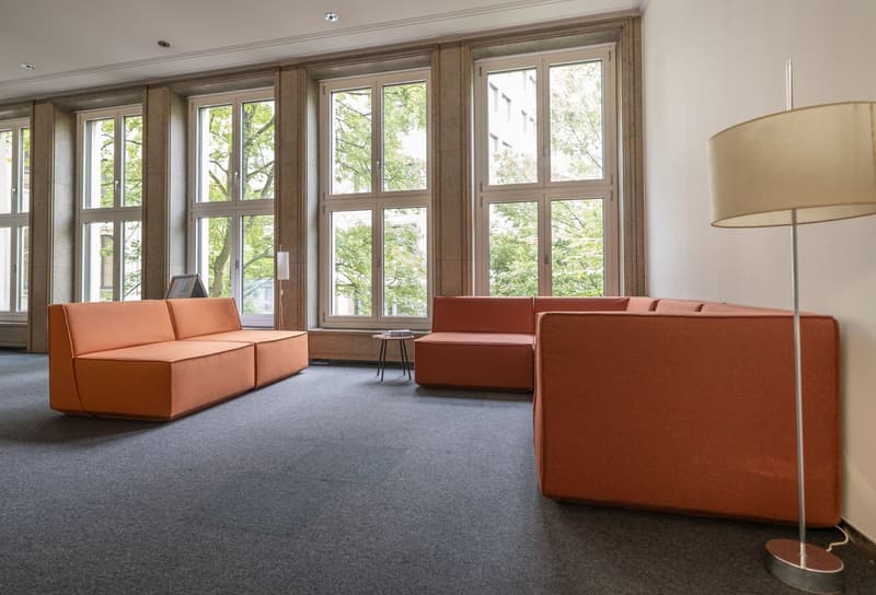 Ample seating, wooden floors, large windows, two couches, and a desk.