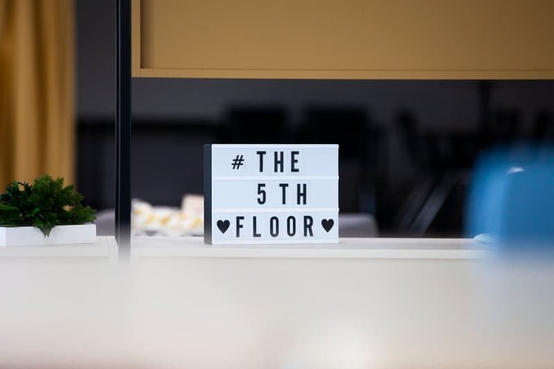 counter with sign board indicating the fifth floor, plant in the left corner, window in the background