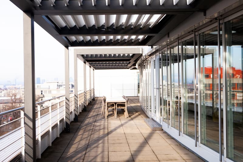 Balcony with tables and chairs, glass windows, covered roof