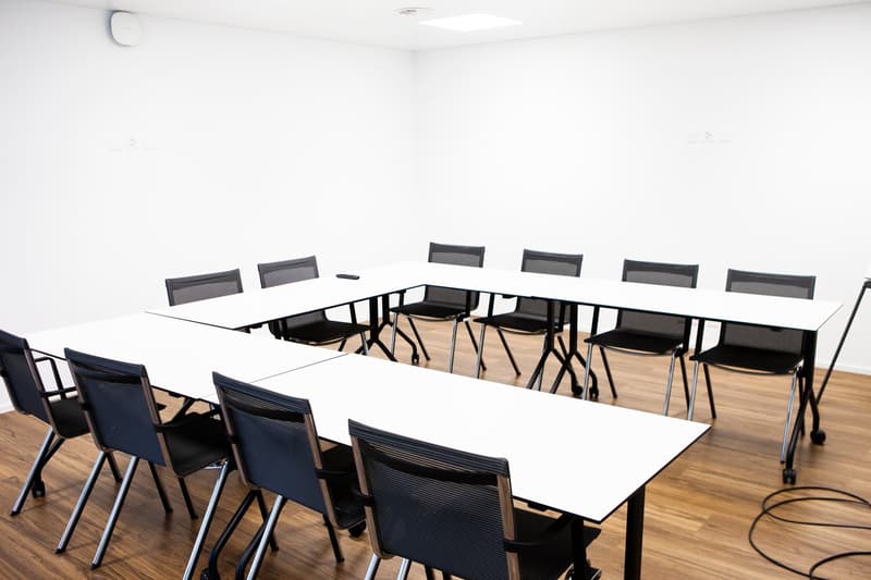 Conference table, black chairs, hardwood floor, empty room, white walls