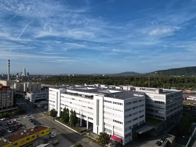 multi-story building, modern architectural design, multiple floors, large windows, solar panels on the roof, green roof area