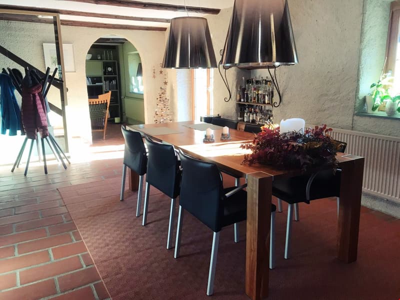 dining room with large table, black chairs, red brick floor, white radiator, dark lamps