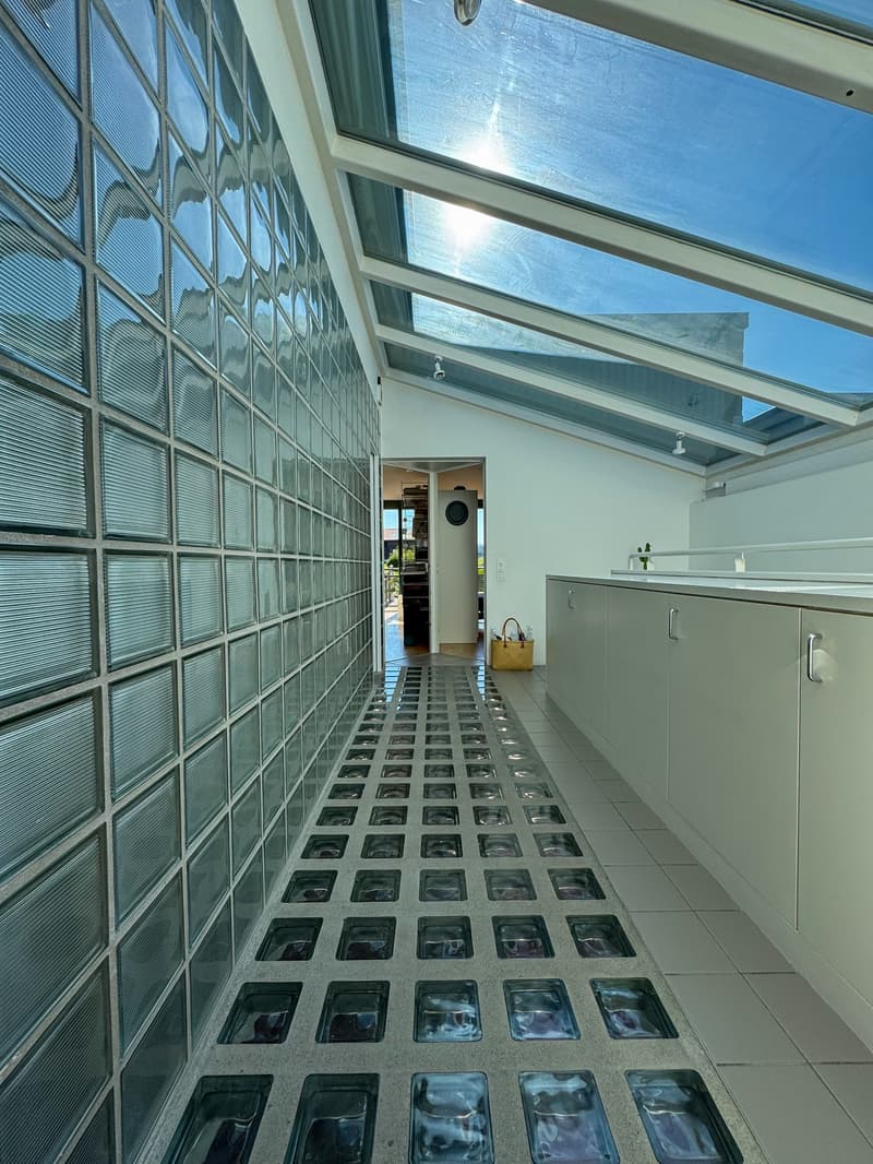 Modern house, glass wall, glass floor, white walls, ceiling windows, kitchen with countertop and cabinets, basket on floor