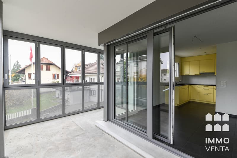 / a modern home with large windows and sliding glass doors leading to a balcony and kitchen