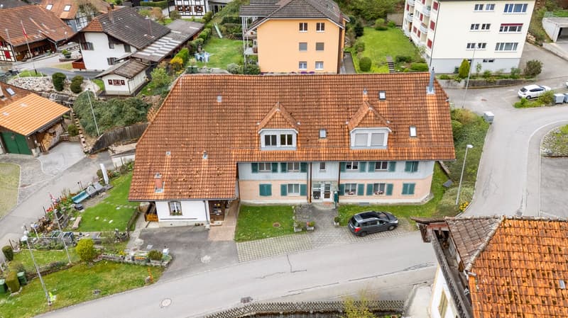 2 story house, brown roof, beige walls, green shutters, car parked in front, garden, street