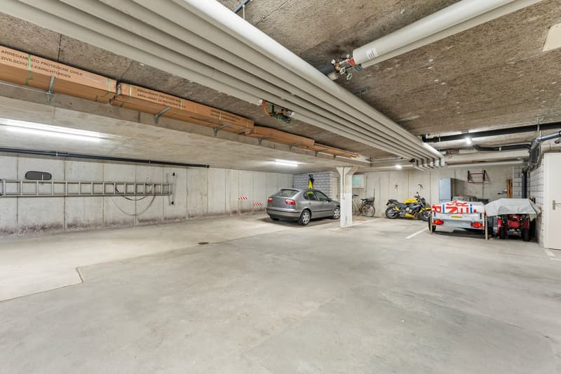 underground parking lot, concrete walls, pipes, car, bicycles, trailer