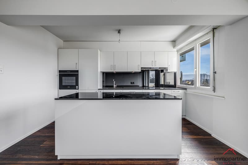modern kitchen with white cabinets, black countertops, built-in oven, refrigerator, and dishwasher, large window with city view