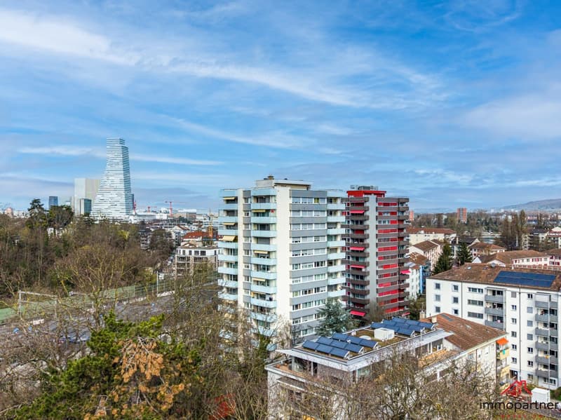 Aerial view of a city with multiple high-rise buildings, solar panels on rooftops, and a clear blue sky.