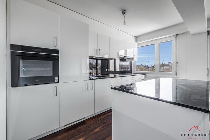 modern kitchen with white cabinets, black countertops, integrated Siemens oven, large window with city view