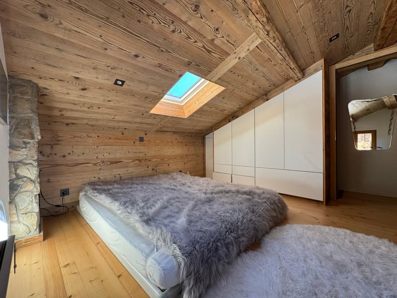 wooden floor, wooden ceiling, large bed, skylit ceiling, stone wall, wardrobe, two rugs