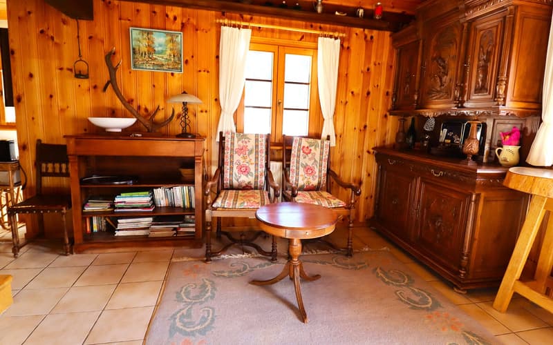 Wood paneling, bookshelf, armchairs, coffee table, wooden desk, picture frame, window with curtains