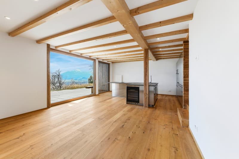 Open kitchen with large windows, wooden floor, wooden beams, stainless steel appliances