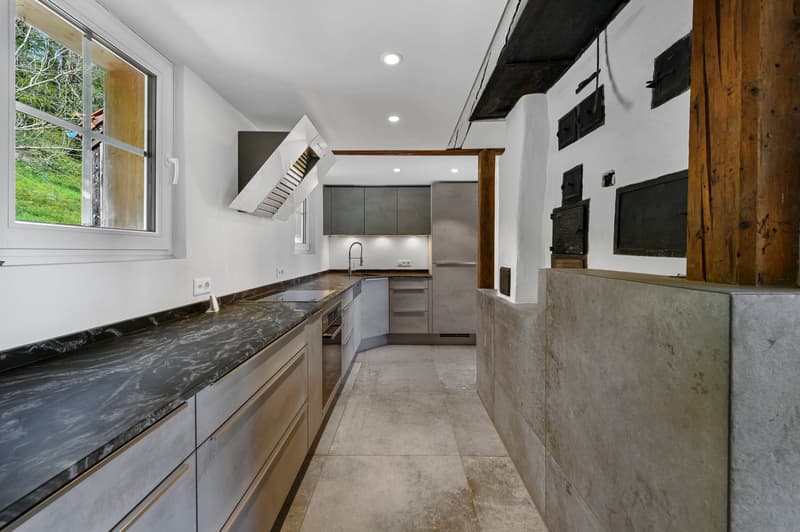 modern kitchen with marble countertop, stainless steel appliances, wooden beams, large window