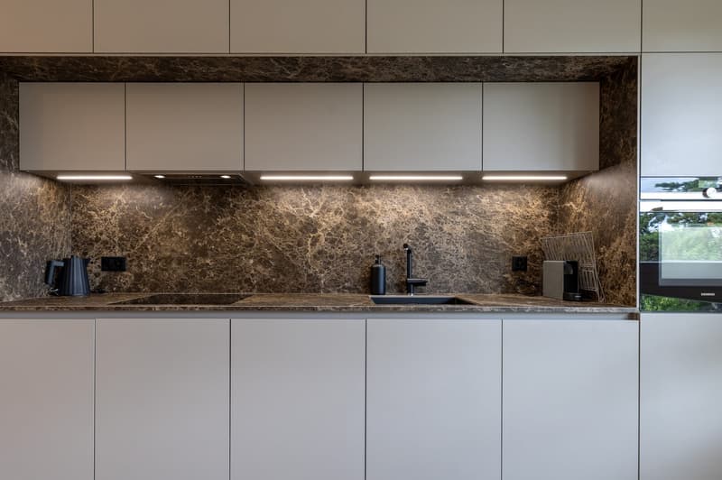 modern white kitchen, marble countertop, stainless steel sink, under cabinet lighting, built-in oven