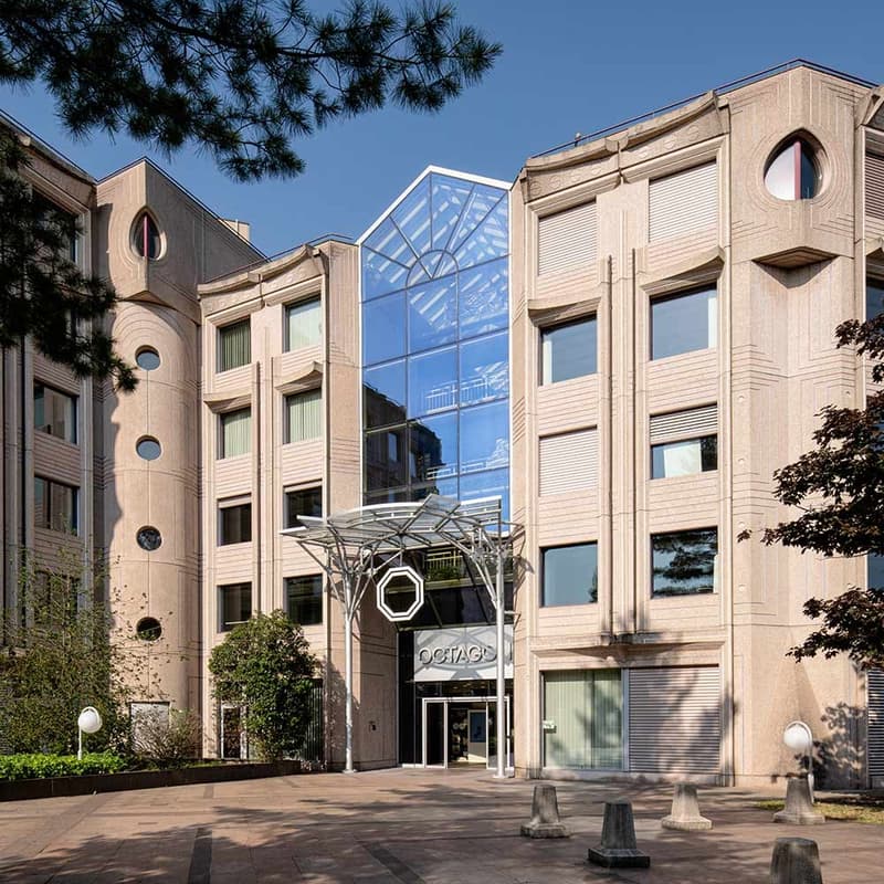 Modern, 3 story building, arched windows, glass wall at entrance, large garden,  trees, lamps
