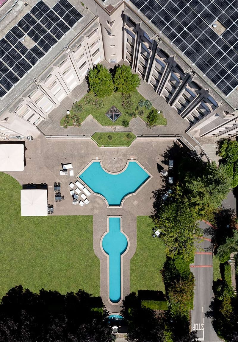 aeral view of building and garden, rectangular swimming pool, solar panels, trees, plants