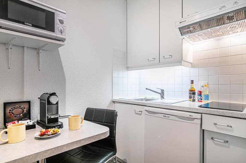 Dishwasher, Microwave, sink, stove, kitchen appliances, table with yellow mugs, black chair